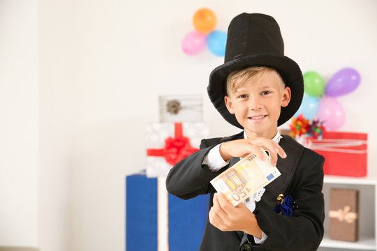 Cute Little Magician Showing Trick With Money Indoors