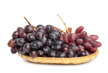 Wicker plate with ripe sweet grapes on white background