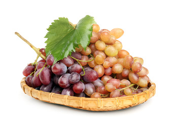 Wicker plate with ripe sweet grapes on white background