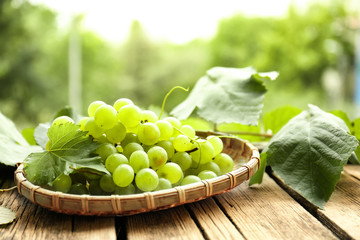Plate with sweet grapes on wooden table outdoors