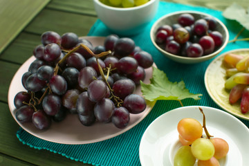 Plates with different sweet grapes on table