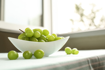 Bowl with sweet grapes on table