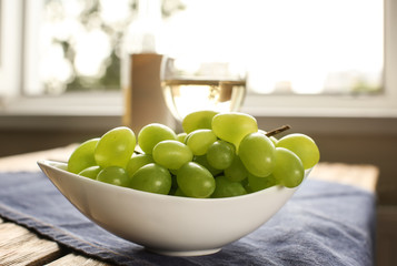 Bowl with sweet grapes on table