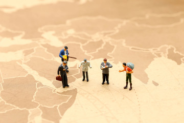 Miniature people : traveler reading a map using concept of Map Reading Week.