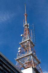 Bellow view of a giant television antenna/tower with a blue sky in the background. Communication, engineering and technology as a concept