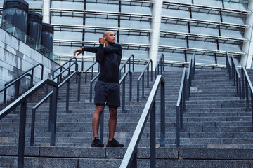 Feel the burn in this muscles. Full length of young man in sportswear doing stretching against industrial city view