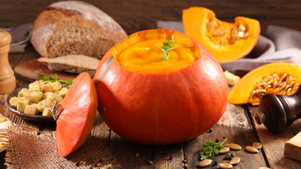 pumpkin soup with bread on wood background