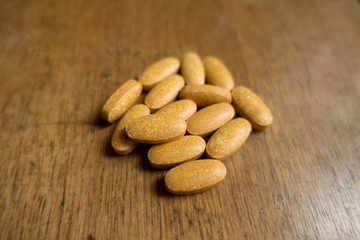 Fistful of big multivitamin pills on wood