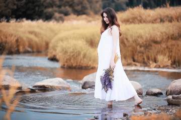 Pregnant woman in nature for a walk in the autumn