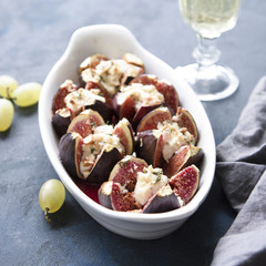 Figs baked with goat cheese, walnuts, honey and thyme on dark blue background.