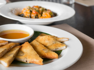 close up of crispy spring roll stuffed with prawns and pork on a white plate in a restaurant