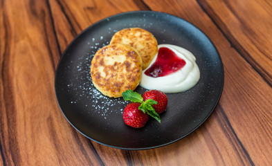 Cottage cheese pancakes. Russian syrniki with cranberry jam and yogurt, selective focus.