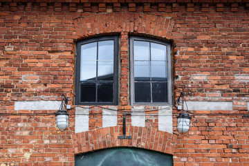 Fragment of vintage brick wall with windows. Textural background. Liepaja, Latvia