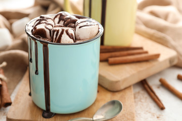 Metal cup of hot chocolate with marshmallows on wooden board