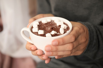 Woman holding cup of hot chocolate with marshmallows, closeup