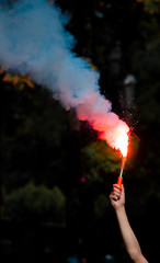 a hand  with lit up bright red light and smoke bomb. revolution. concept of protest