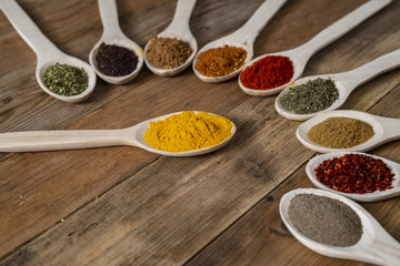 Assorted spices on wooden spoons. Delicious food ingredients.