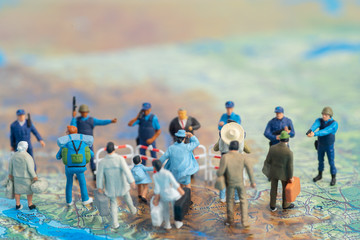 Miniature toy people concept US border patrols against a group of migrant from Mexico - obrazy, fototapety, plakaty