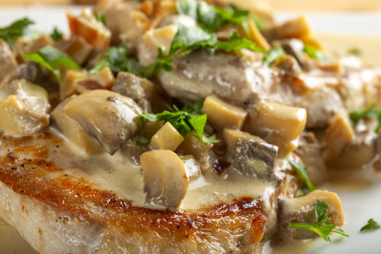 Fried pork meat with sour cream sauce, mushrooms and green parsley