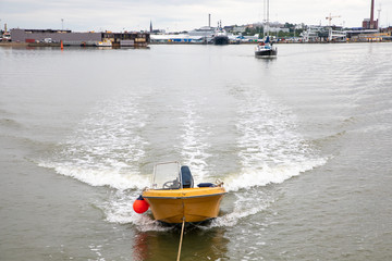 Looking from the stern of a 3-masted schooner at a dinghy pulled behind; on its way under motor...