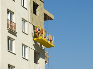 Construction worker at construction site using lifting boom machinery