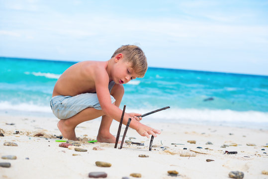 boy playing with natural sticks. blue sea white sand
