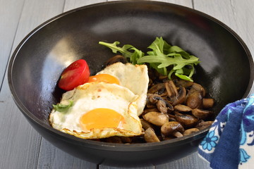Fried egg with mushrooms in frying pan for breakfast