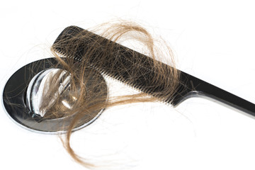 Hair loss on washbasin. Long brown hair with black comb on white basin in the bathroom.
