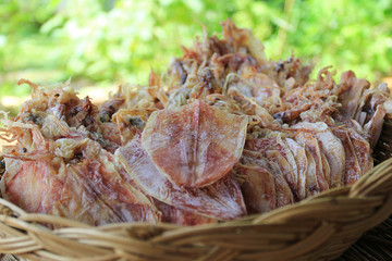 Dried squid in a basket on natural green background