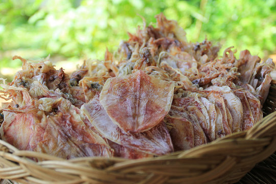 Dried squid in a basket on natural green background
