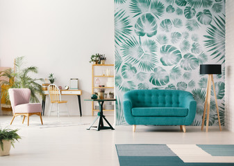 White living room interior with leafy wallpaper in the real photo with turquoise sofa, fresh plants, wooden desk and empty wall with place for your poster - obrazy, fototapety, plakaty