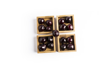 group of fresh red cherries in a wooden square bowls on a white background
