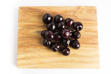 group of fresh red cherries on a wooden board on a white background

