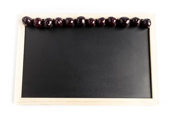 Obraz premium group of fresh red cherries in a row on a black chalkboard with a white background 