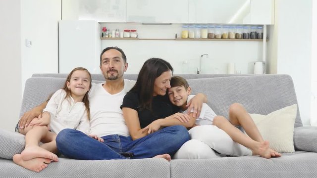 Happy young family sitting on the sofa. Happy family spending time together at home. Mother, father, son, daughter