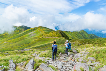 緑の山を撮影する人々