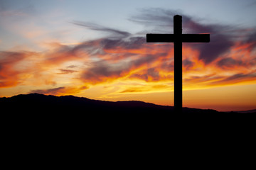 Religion theme, view of catholic cross in black shadow, with fantastic sunset with warm colors and mountains as background, in Viseu, Portugal - obrazy, fototapety, plakaty