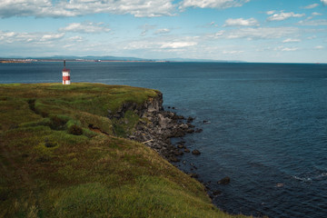 Fototapeta na wymiar Insanely beautiful red and white lighthouse on the rocks on the shores of the Okhotsk Sea in the north of the Khabarovsk Territory of Russia. Beautiful lighthouse