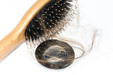 Hair loss on washbasin. Long brown hair with wood brush on white basin in the bathroom.