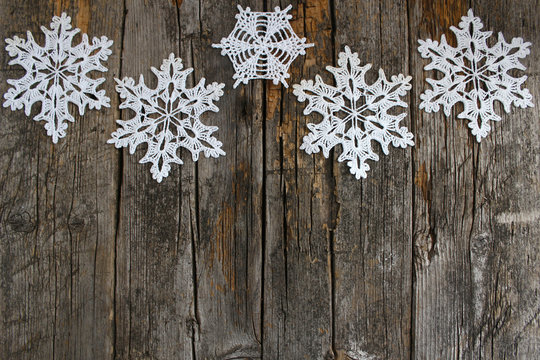 White crochet snowflakes on vintage rural wooden background. The concept of the celebration, new year and Christmas