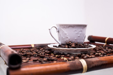 White cup with coffee and coffee beans on a brown stand