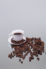 White cup with coffee. Coffee beans. Reflection in the mirror.