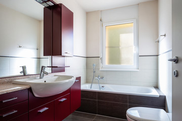 Bathroom with red wardrobe, bathtub and window