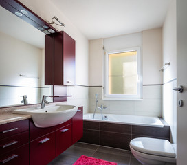 Bathroom with red wardrobe, bathtub and window