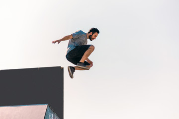 Sportive man make parkour tricks while jumping