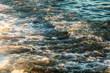 Waves at sea in the rays of sunset