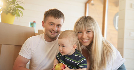 Portrait of happy family at home, sitting on floor and playing together.