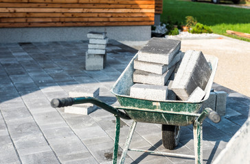 Laying gray concrete paving slabs in house courtyard driveway patio.