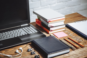 Workplace of student, secretary in office, manager. Laptop, books, headphones, notebook and stationery on a wooden table.