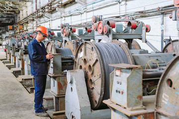 Fototapeta premium Wire rod, fittings in warehouses. worker alongside a bundle with catalkoy. industrial storehouse at the metallurgical plant.